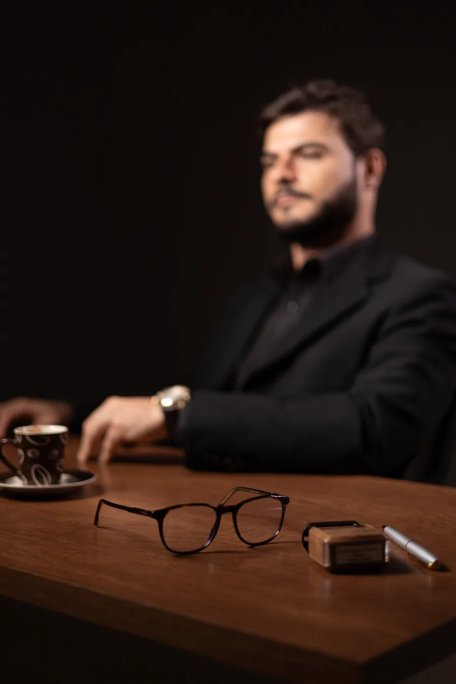 Mesa do consultório com café, óculos e o carimbo profissional.
