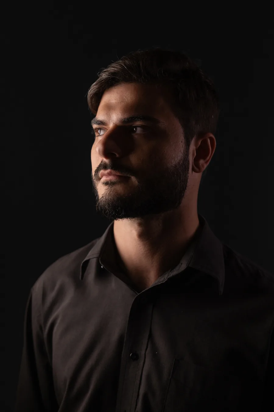 Guilherme Creimer em retrato de estúdio sobre fundo escuro.